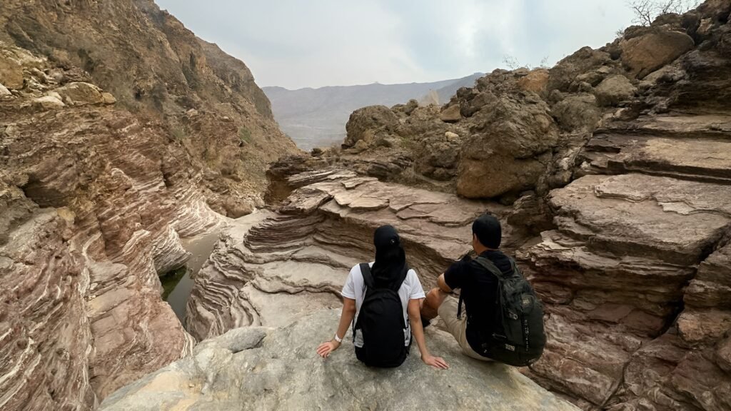 Two hikers resting on rocky trails in Fujairah’s Hajar Mountains