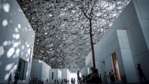The inside of Louvre Abu Dhabi with people looking at the ceiling 
