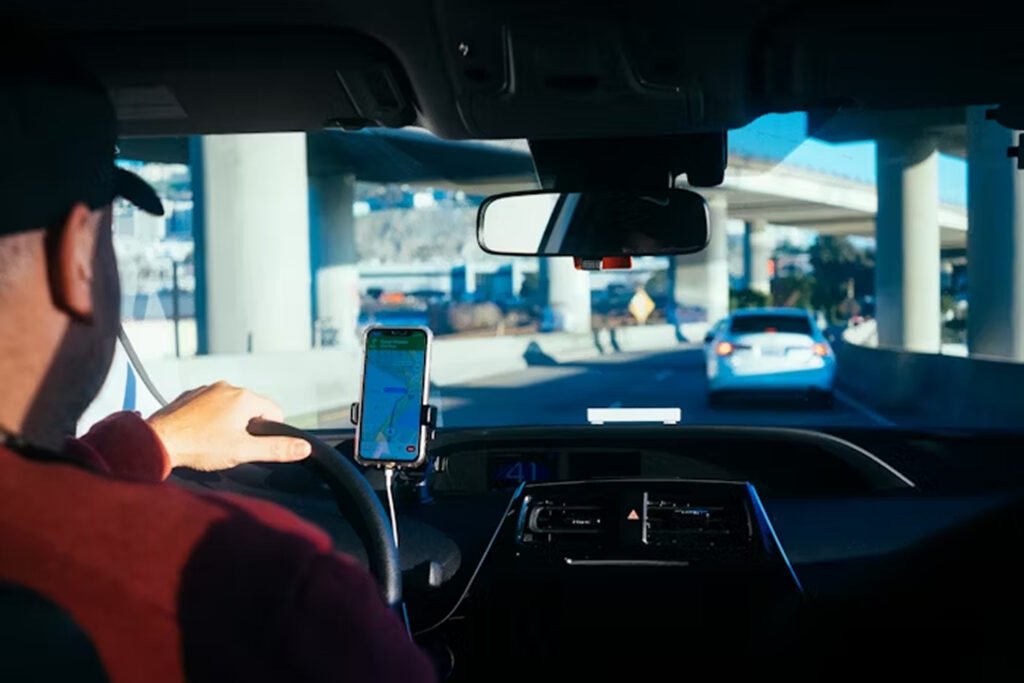 A driver driving the car with a phone on charge in front