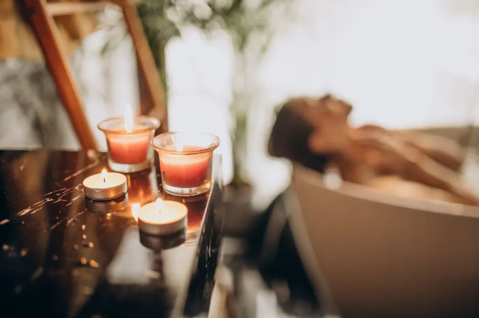A woman enjoying a spa treatment with candles lit on the shelf
