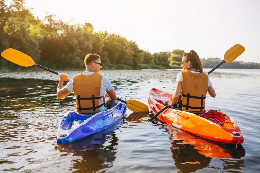 A man and a woman kayaking in the river with their kayaks and paddles