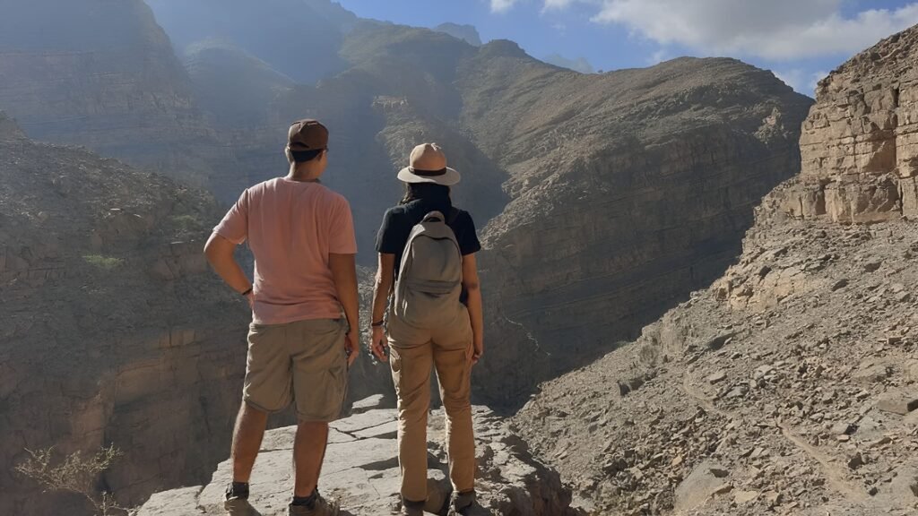 Two hikers stand on a rocky cliff in Ras Al Khaimah