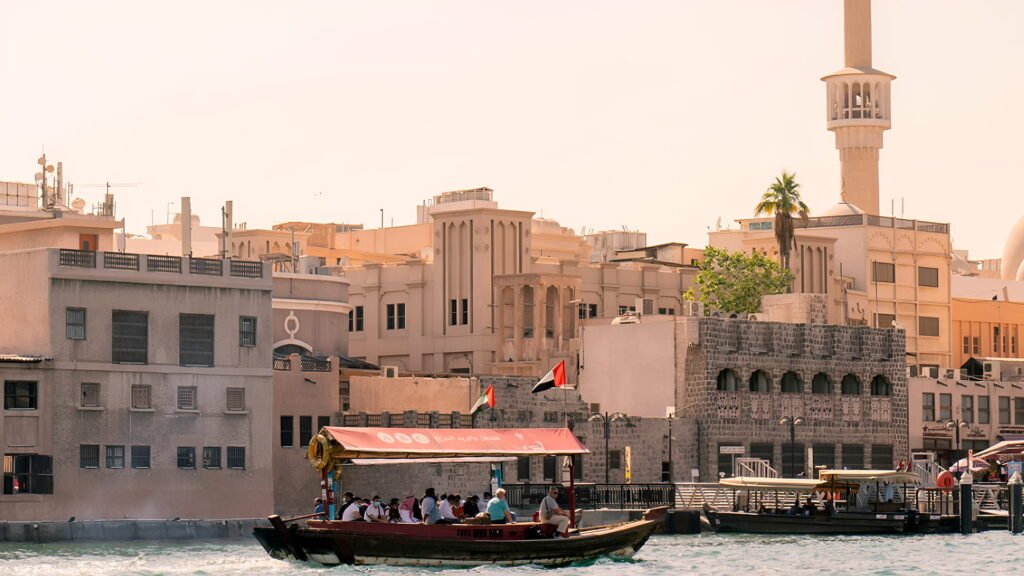 Traditional wooden abra boat sailing on Dubai Creek with historic Old Dubai buildings